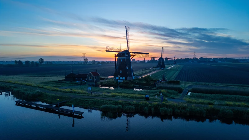 Windmühlen bei Sonnenaufgang am Wasser